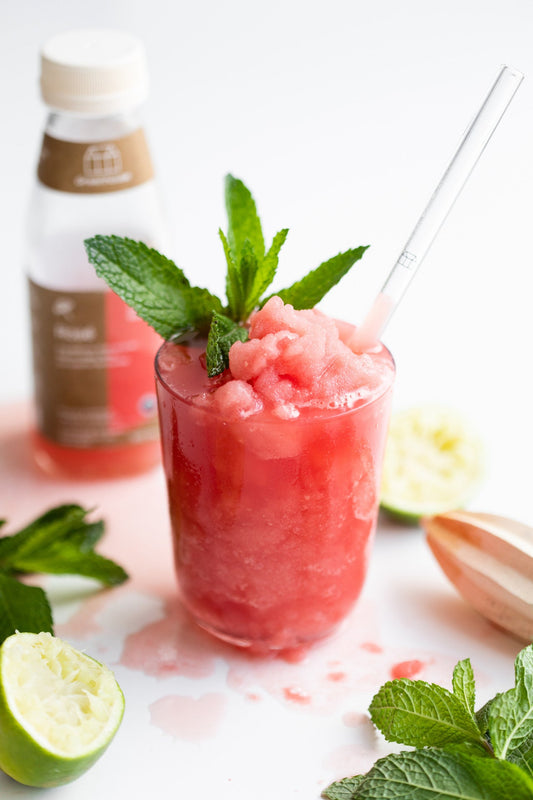 A slushy red drink garnished with mint leaves 