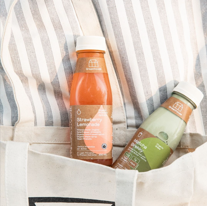 Strawberry lemonade and matcha brekky drinks peeking out of a tote bag.